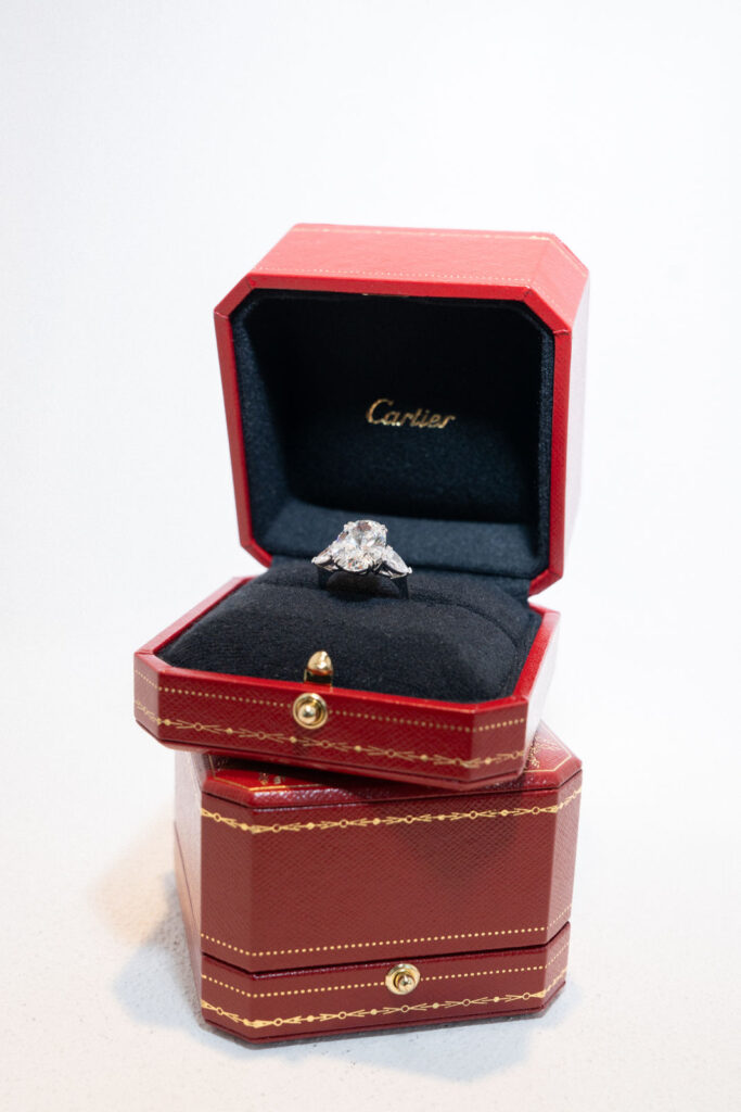 Diamond ring in a red Cartier box, with another matching box underneath, on a white background.