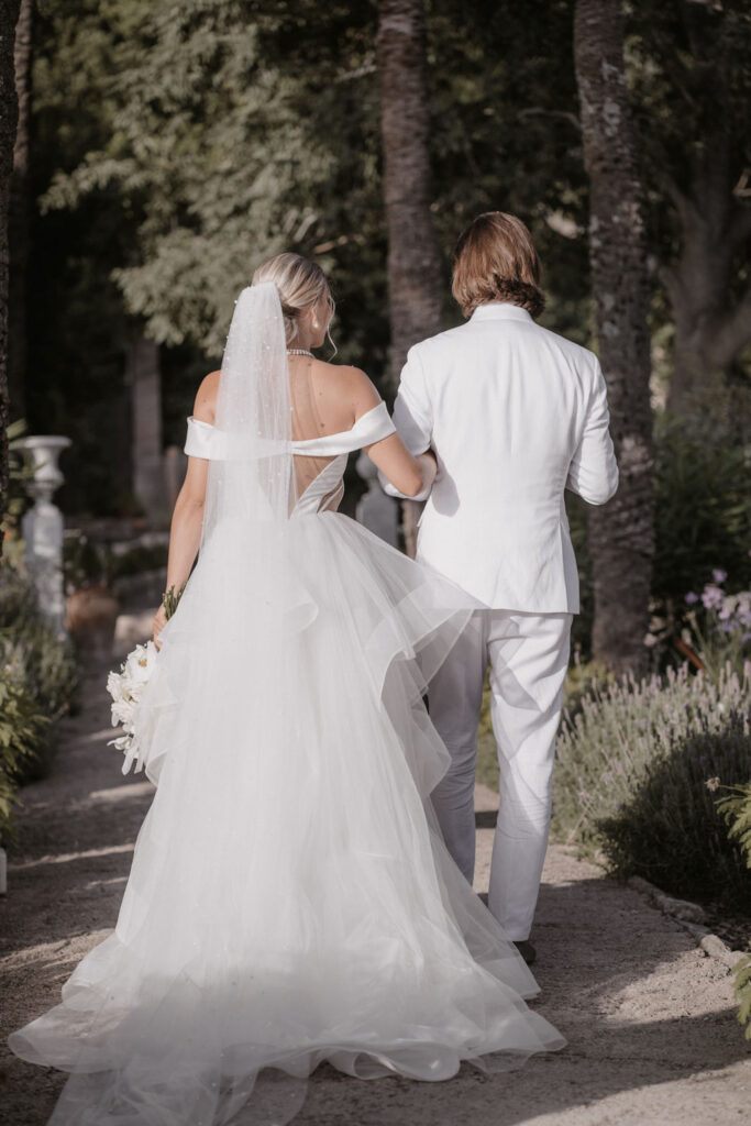 Wedding in Son Marroig: Getting married over the cliffs of Mallorca, with experiences, costs and tips 8 A couple in white is walking arm in arm along a garden path in Son Marroig.