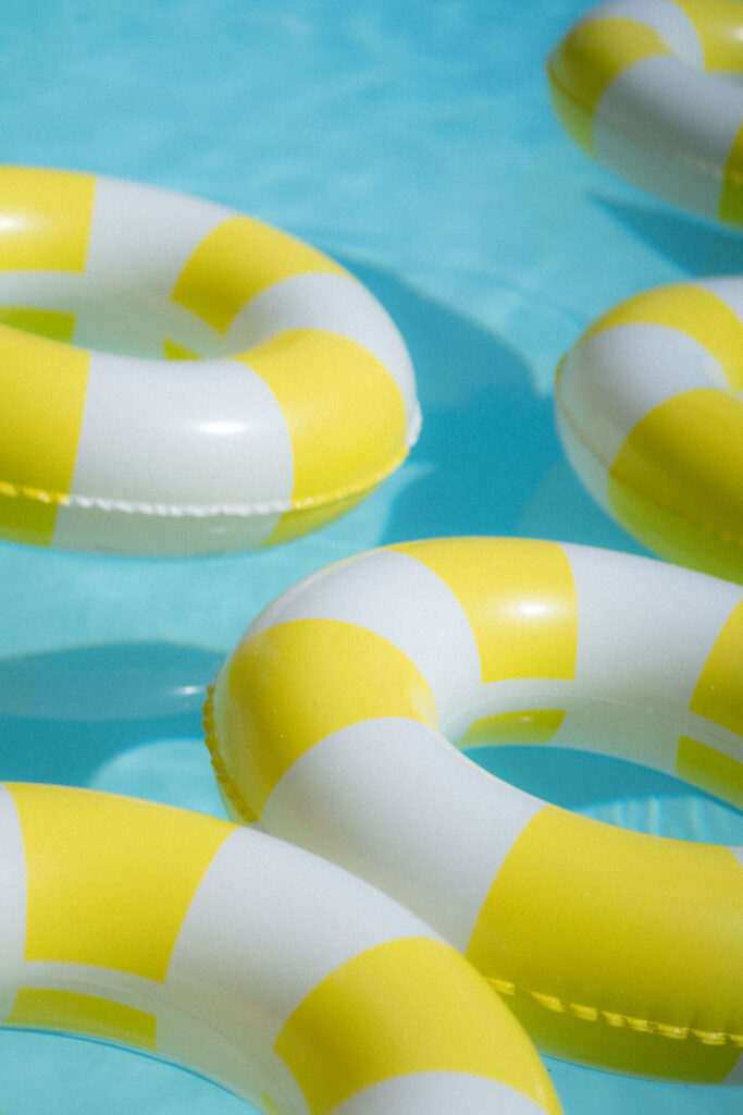 Yellow and white inflatable pool rings floating on clear, blue water create a playful backdrop, perfect for destination weddings or abroad wedding photography.