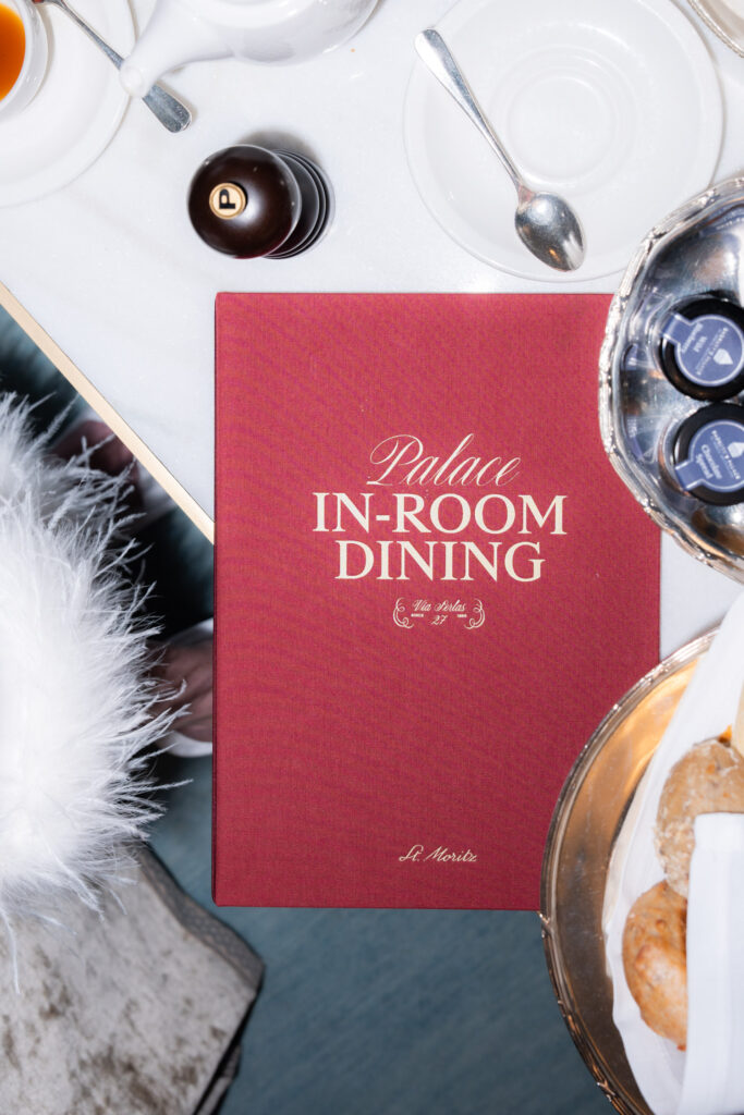 A red Palace in-room dining menu on a table with pastries, tea, and spices - perfect for discussing overseas wedding plans or capturing wedding photography moments abroad.
