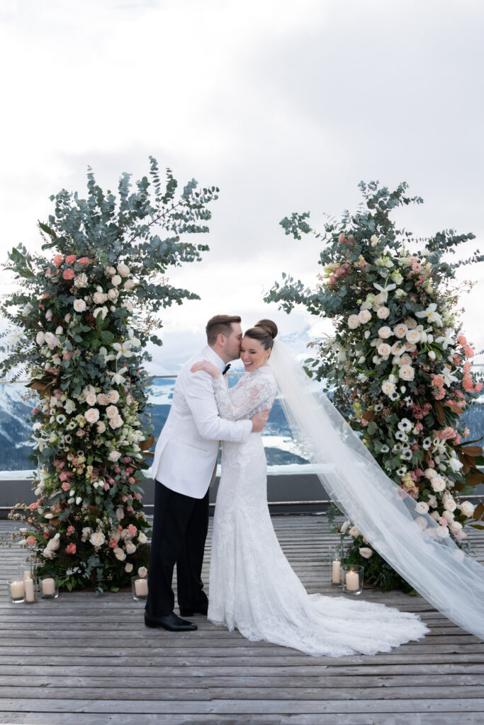 Wedding photographer Austria Bride and groom kiss at an outdoor altar decorated with flowers and greenery - captured in stunning wedding photography by a talented wedding photographer, perfect for an unforgettable destination wedding.