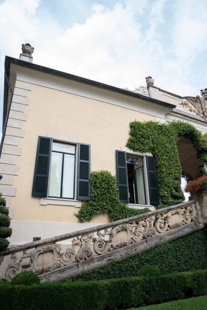 Villa del Balbianello Hochzeit: Kosten, Ablauf und die ikonischste Location am Comer See 44 The Villa del Balbianello, a cream-colored villa with walls covered with vines and an elaborately decorated stone staircase.