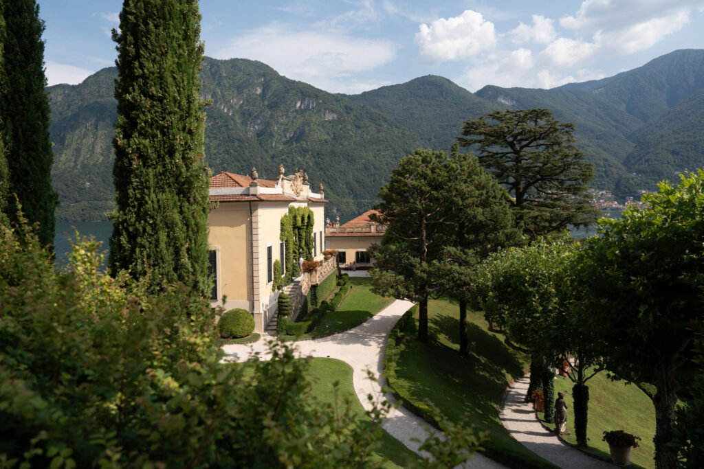 The Villa del Balbianello with terraced gardens and views of a lake and the mountains.