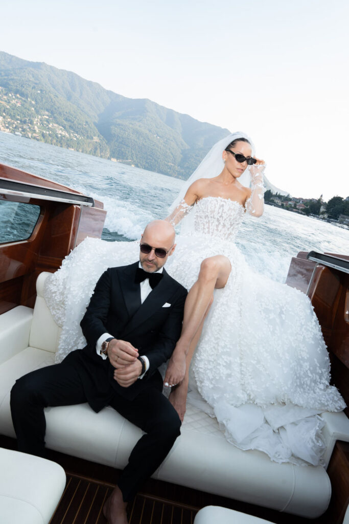 Villa del Balbianello Hochzeit: Kosten, Ablauf und die ikonischste Location am Comer See 12 A couple wearing sunglasses is sailing in a wooden motorboat on the lake from Villa del Balbianello.