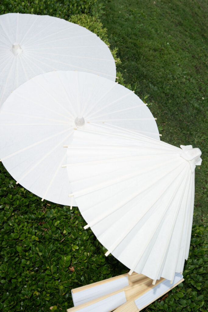 Villa del Balbianello Hochzeit: Kosten, Ablauf und die ikonischste Location am Comer See 54 Three white paper sunshades leaning against a hedge at Villa del Balbianello.