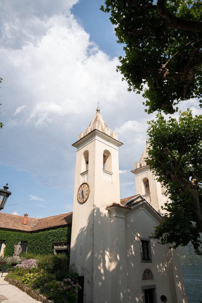 Villa del Balbianello Hochzeit: Kosten, Ablauf und die ikonischste Location am Comer See 48 A stone church with a bell tower near Villa del Balbianello overlooking a lake.