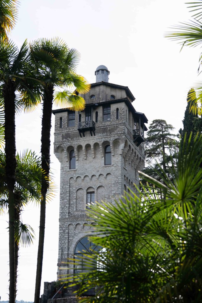 Ein Steinturm mit gewölbten Fenstern, umgeben von Palmen und Grün, an einem hellen Tag - perfekt für einen Hochzeitsfotografen, der atemberaubende Hochzeiten im Ausland oder Ihre Traumhochzeit festhält.