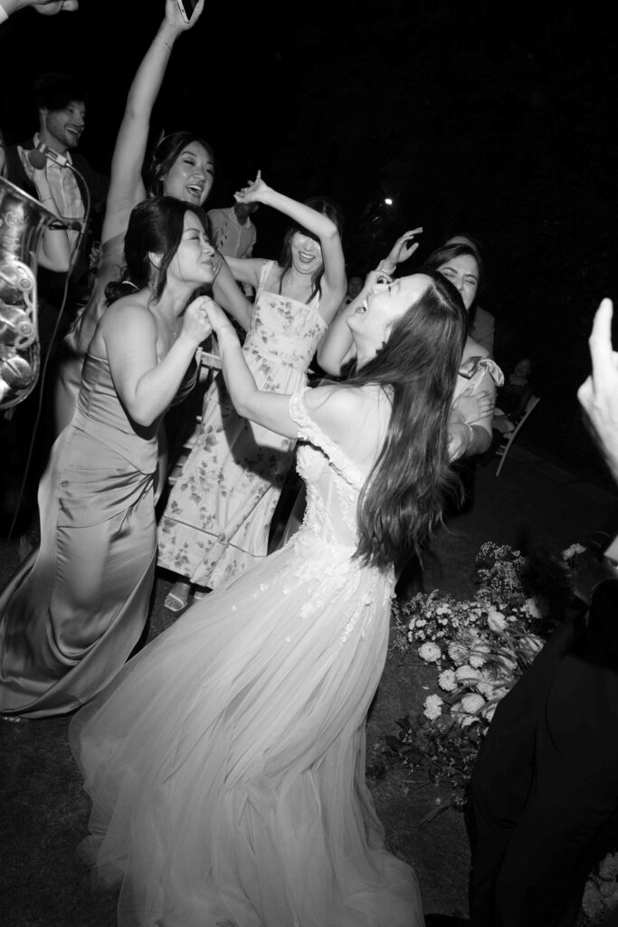 Editorial Wedding Photography: The Trend for Stylish Wedding Photos 10 A group of people in formal attire are dancing and celebrating joyfully at an outdoor night event, capturing the magic of destination weddings with a talented wedding photographer.