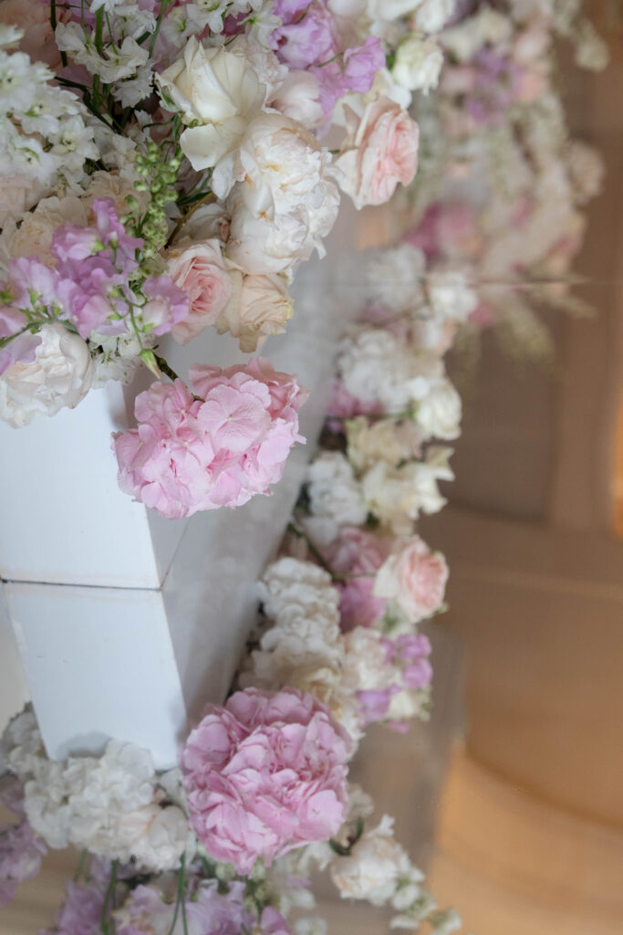 Weiße und rosa Blüten, die am Rand einer weißen Fläche angeordnet sind und sanft im natürlichen Licht erstrahlen, erinnern an die zarte Schönheit eines automatisch gespeicherten Entwurfs – sie fangen einen flüchtigen Moment mit anmutiger Schlichtheit ein.