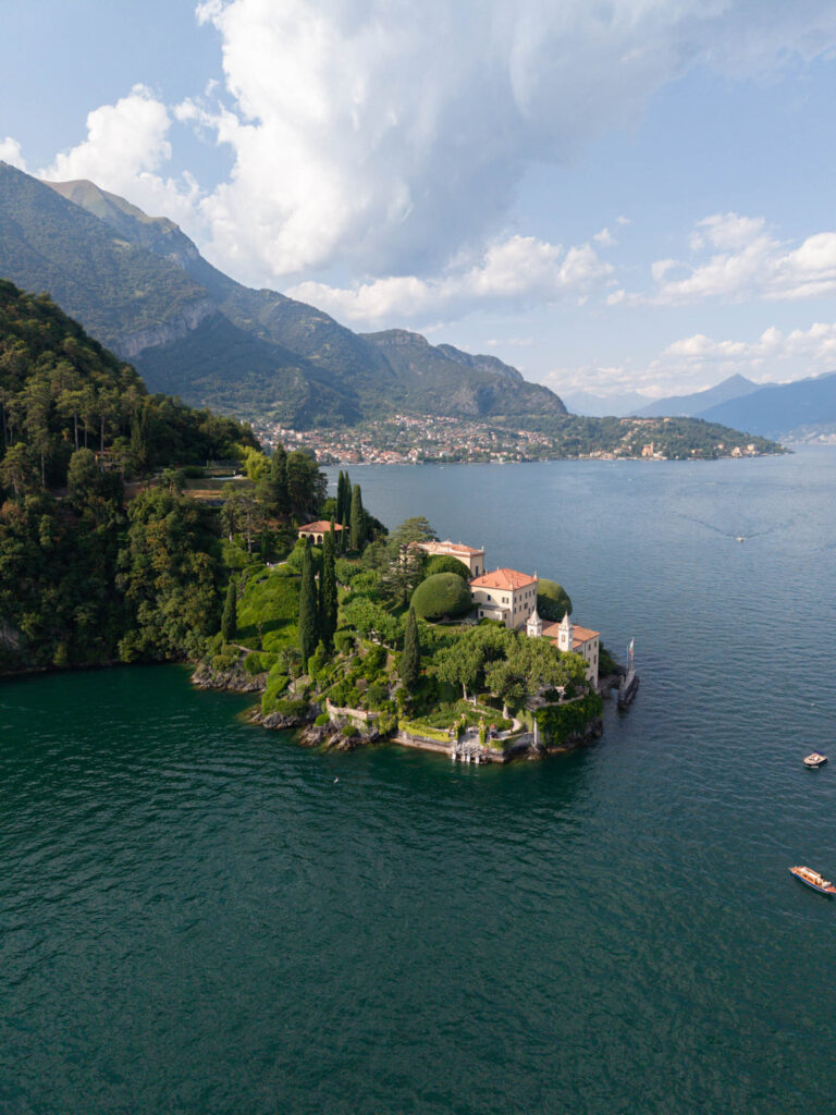 Luftaufnahme einer üppig bewachsenen Villa am Seeufer auf einer kleinen Halbinsel, umgeben von Bergen und ruhigem blauem Wasser – wie ein automatisch gespeicherter Entwurf des Paradieses, perfekt bewahrt im Gedächtnis der Natur.