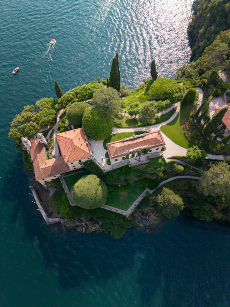 Luftaufnahme einer Villa mit Gartenanlage auf einer üppig bewachsenen Halbinsel, umgeben von tiefblauem Seewasser – eingefangen in einem automatisch gespeicherten Entwurf, der mühelose Eleganz und natürliche Schönheit vermittelt.