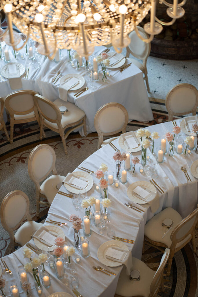 Elegante Tische, gedeckt mit weißer Tischwäsche, Kerzen und Blumen unter einem Kronleuchter, von oben betrachtet – perfekt für eine Hochzeit in Bonn im atemberaubenden Stella Rheni.