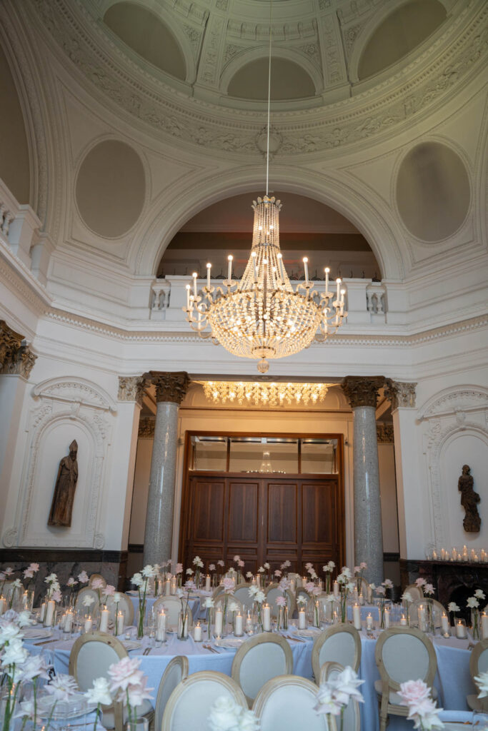 Ein eleganter Speisesaal mit einem prächtigen Kronleuchter, einer gewölbten Decke und mit Blumen geschmückten Tischen, die für eine Veranstaltung gedeckt sind – perfekt für eine stilvolle Hochzeit im Stella Rheni und für alle, die davon träumen, in Bonn zu heiraten.