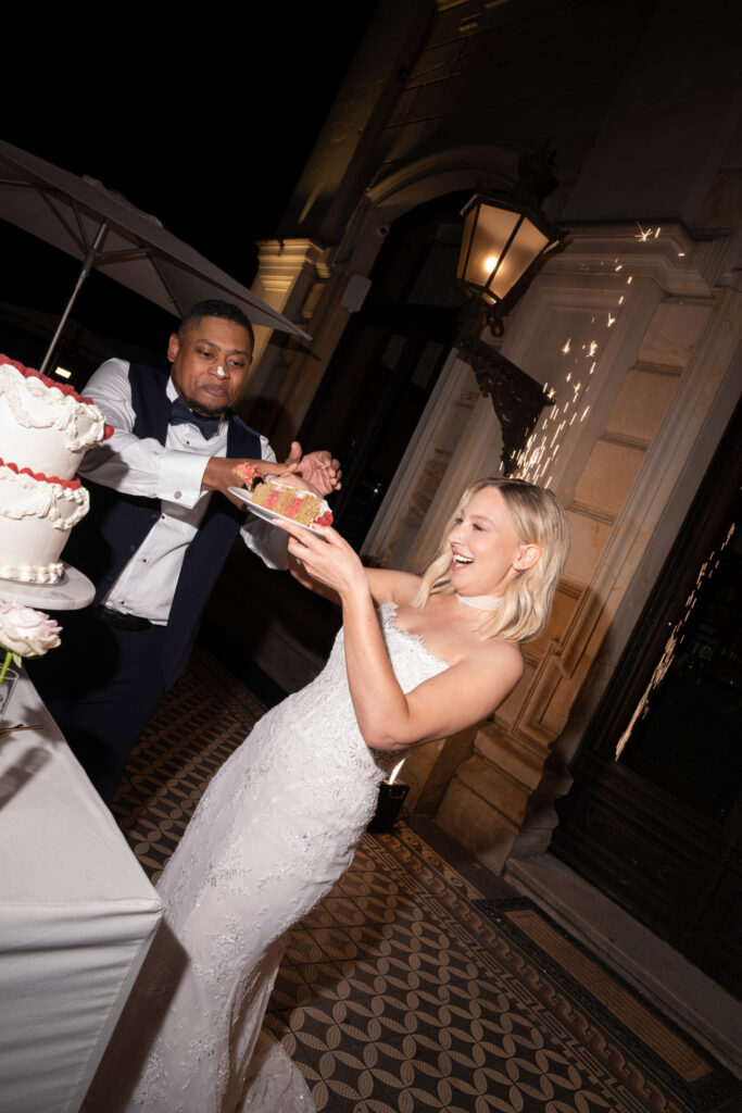 Braut und Bräutigam lachen, als die Braut bei ihrer Hochzeit im eleganten „Stella Rheni“ dem Bräutigam spielerisch ein Stück Torte entgegen schiebt – so feiern sie ihren besonderen Tag bei ihrer Hochzeit in Bonn.