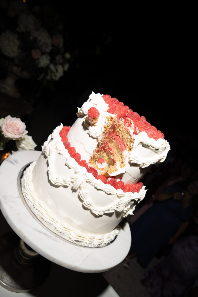 Bei einer zweistöckigen Torte mit Himbeeren oben ist ein Stück herausgeschnitten, sodass man die Schichten im Inneren sehen kann – eine elegante Wahl für eine Feier wie die „Hochzeit Bonn“ im Stella Rheni.