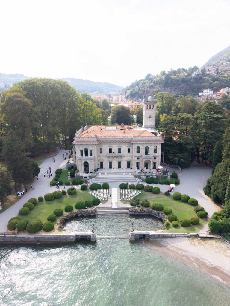 Luftaufnahme einer prächtigen Villa am See mit Automatischer Entwurf, formalen Gärten und einem Turm.