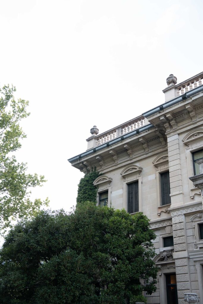 A historic stone building with ornate details, its lower facade adorned with automatic design motifs and plants.