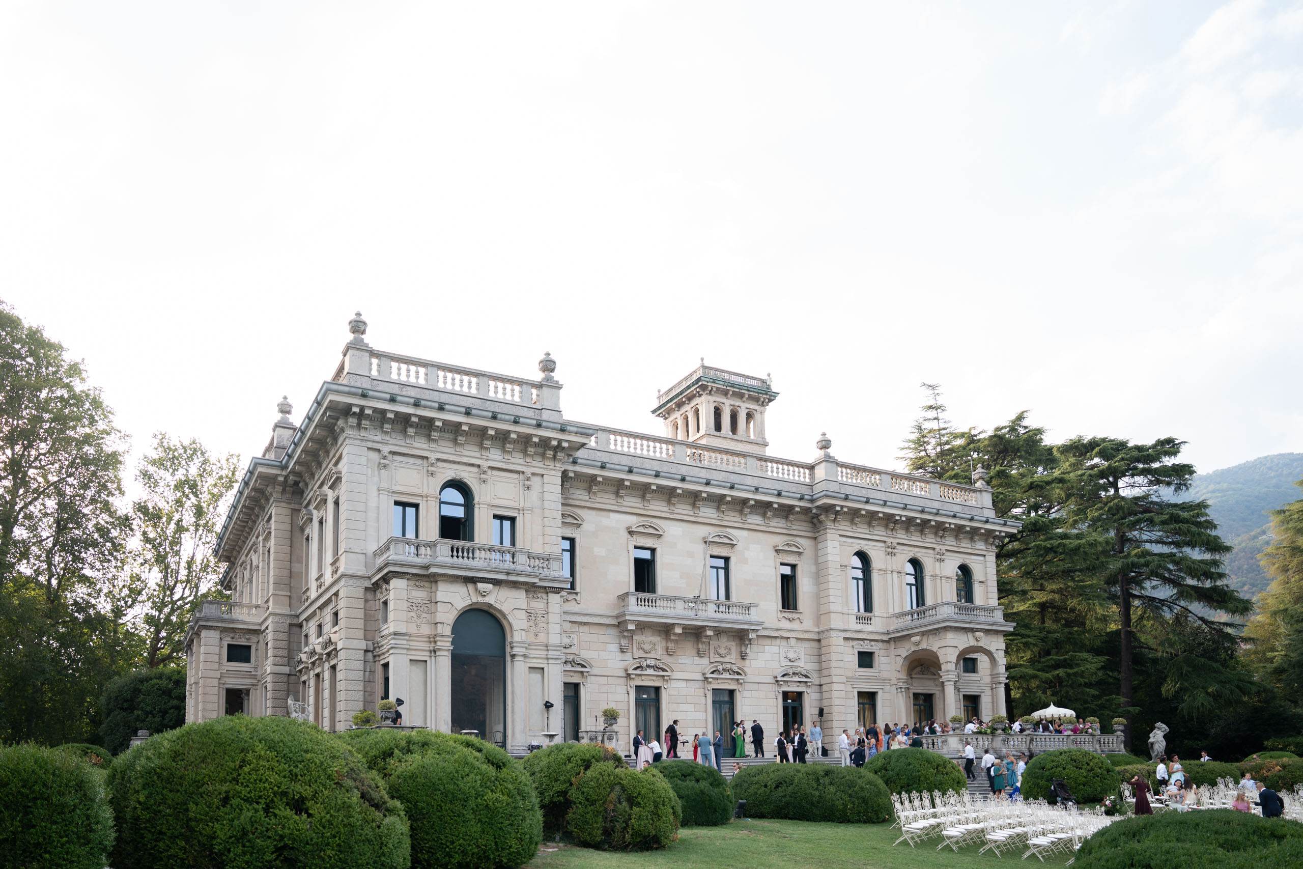 Großes historisches Herrenhaus mit Bogenfenstern, automatischer Entwurf, Gärten und Menschen, die sich draußen versammelt haben.