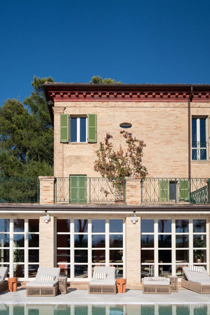 Hochzeit im Maniero Montecassiano: Euer Hochzeitswochenende in einer Boutique-Villa in den Marken 8 Villa Brick Maniero Montecassiano mit grünen Fensterläden, einem Balkon und Liegestühlen am Pool.