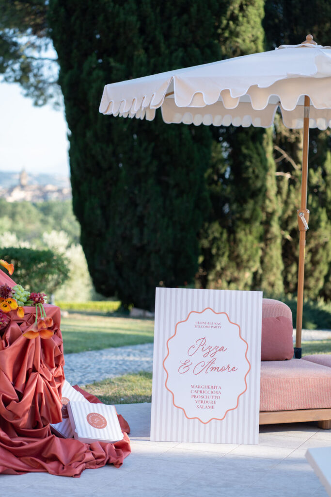 Hochzeit im Maniero Montecassiano: Euer Hochzeitswochenende in einer Boutique-Villa in den Marken 46 Ein Hochzeitsschild von Maniero Montecassiano, auf dem neben einem Sonnenschirm verschiedene Pizzasorten aufgeführt sind.