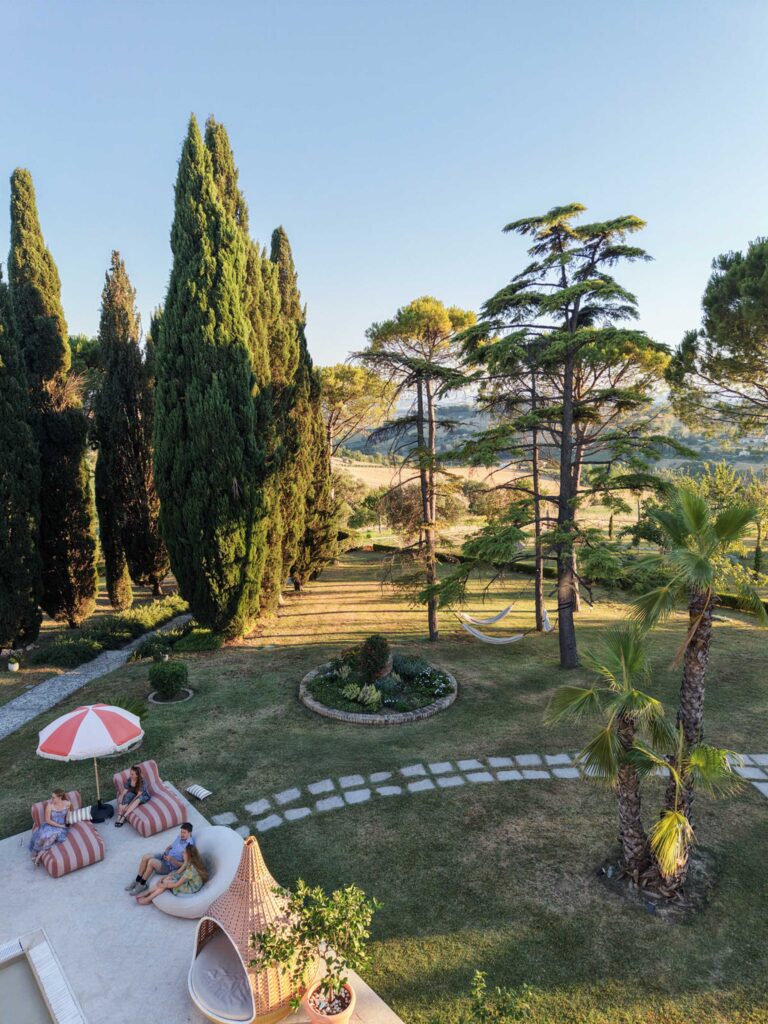 Hochzeit im Maniero Montecassiano: Euer Hochzeitswochenende in einer Boutique-Villa in den Marken 6 Vier Personen, die sich auf den Liegestühlen im Garten des Maniero Montecassiano entspannen.