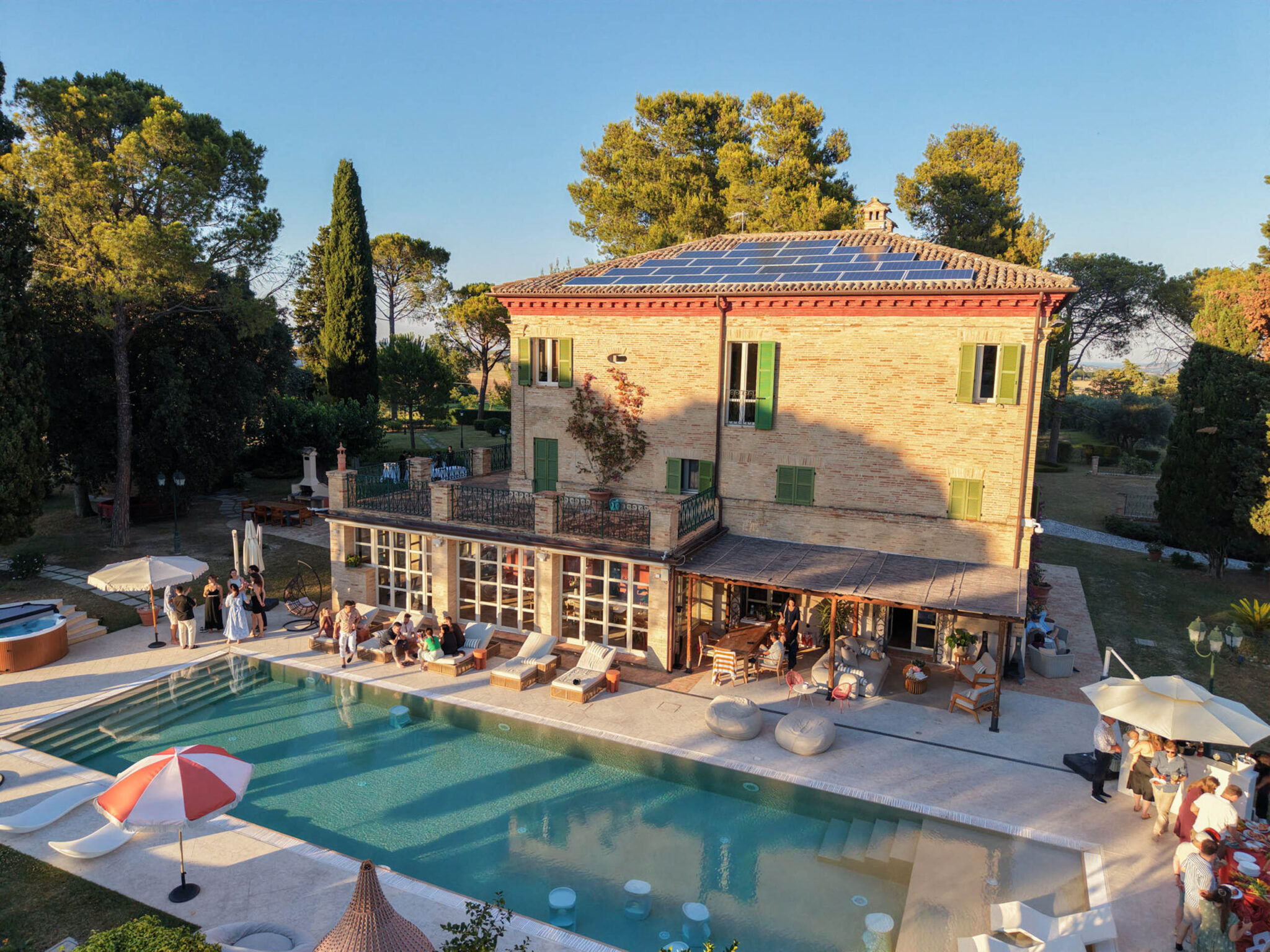 Eine kleine Villa aus Ziegelsteinen mit Sonnenkollektoren und Blick auf einen Pool an einem Hochzeitswochenende.
