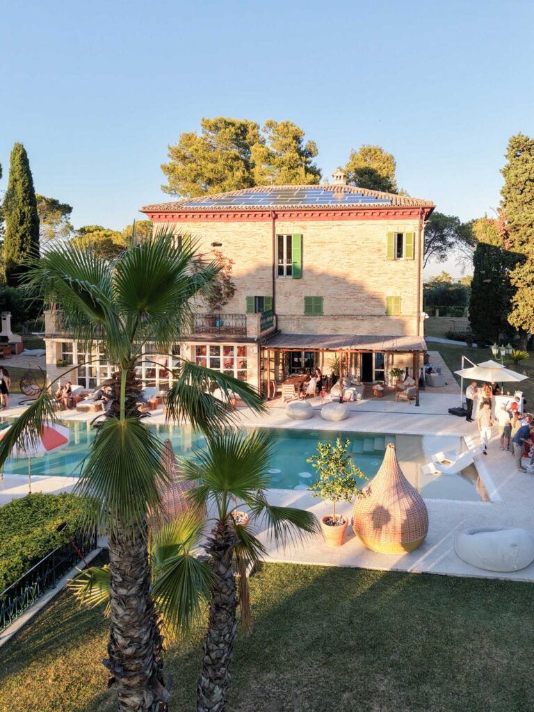 Hochzeit im Maniero Montecassiano: Euer Hochzeitswochenende in einer Boutique-Villa in den Marken 52 Eine Steinvilla in Maniero Montecassiano mit einem Pool und Menschen, die sich auf der Terrasse unterhalten.