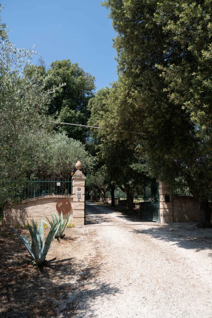 Hochzeit im Maniero Montecassiano: Euer Hochzeitswochenende in einer Boutique-Villa in den Marken 5 Eine Schotterauffahrt führt durch das Tor aus Stein und Metall des Maniero Montecassiano.