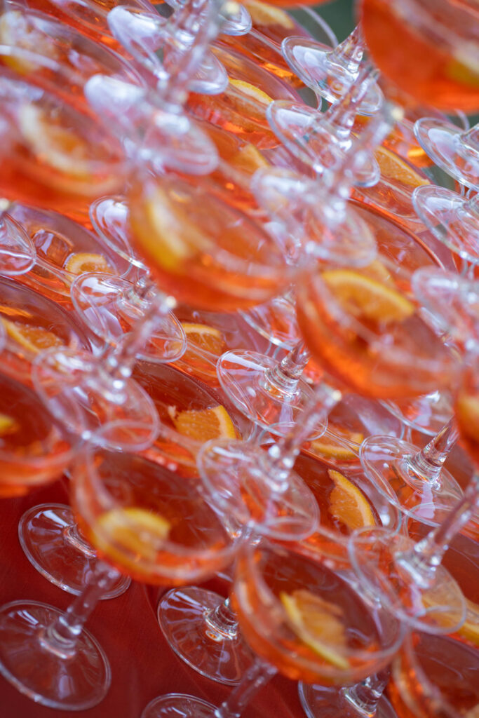 Hochzeit im Maniero Montecassiano: Euer Hochzeitswochenende in einer Boutique-Villa in den Marken 53 Im Maniero Montecassiano steht ein hoher Turm aus orangefarbenen Cocktailgläsern, die jeweils mit einer Orangenscheibe garniert sind.