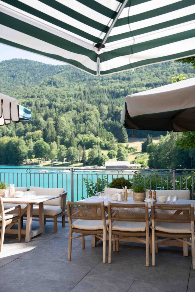 Speisen im Freien auf der Terrasse des Rosewood Schloss Fuschl mit Blick auf den See und die bewaldeten Berge.