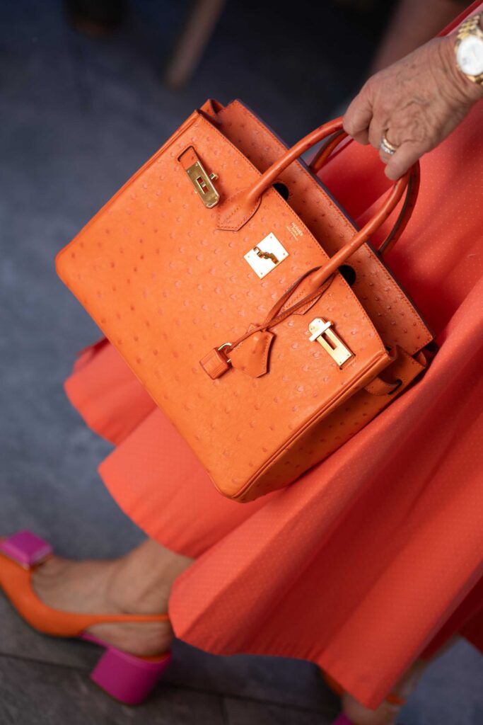 Eine Person mit einer orangefarbenen, strukturierten Handtasche bei einer Hochzeit im Rosewood Schloss Fuschl.