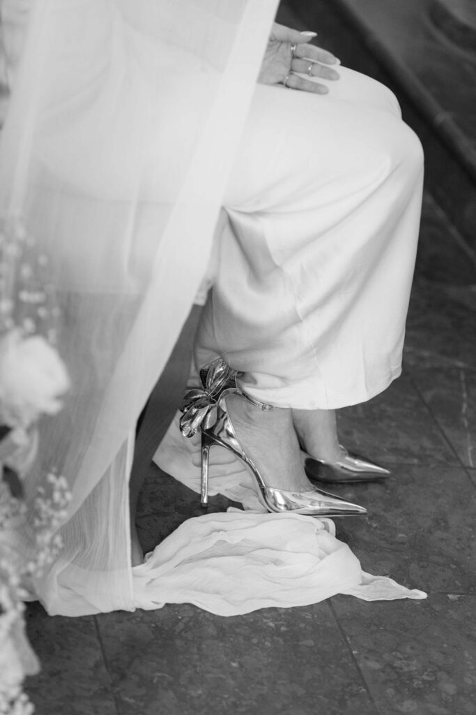 Braut in weißer Hose und silbernen Pumps mit Schleife bei einer Hochzeit im Schloss Fuschl.