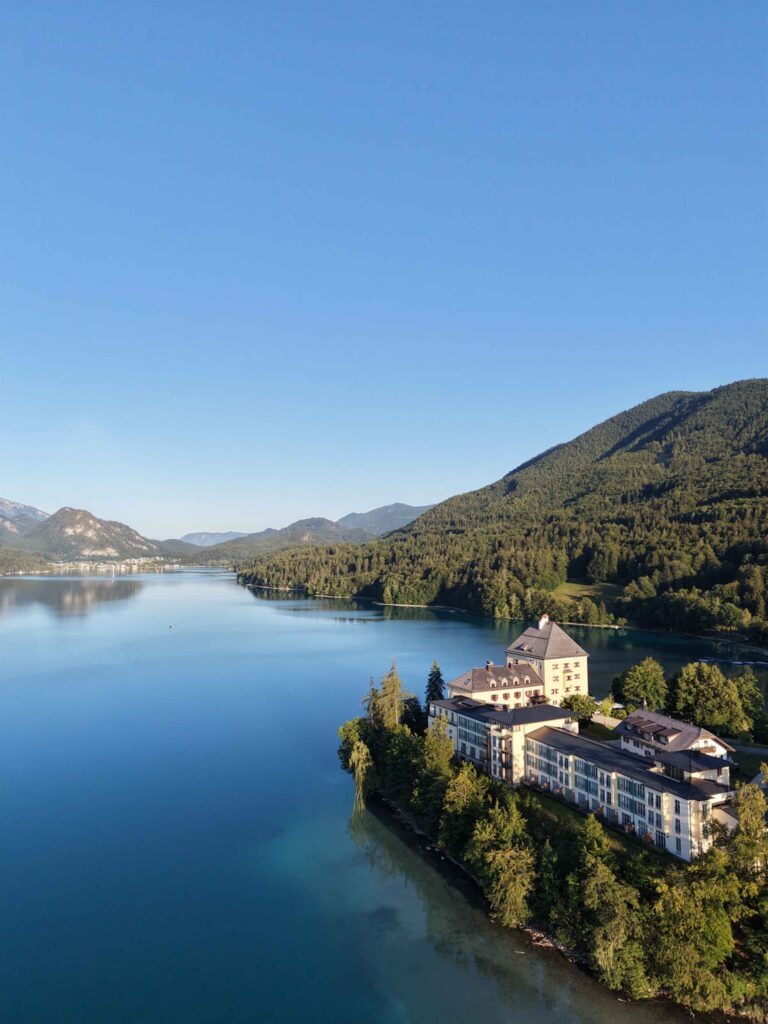 Das Rosewood Schloss Fuschl liegt auf einer bewaldeten Landzunge, die in einen von Bergen umgebenen See hineinragt.