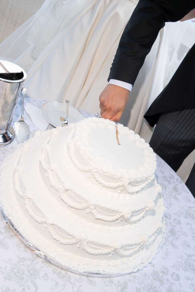 Ein Brautpaar schneidet bei seiner Hochzeit im Rosewood Schloss Fuschl eine mehrstöckige Hochzeitstorte an.