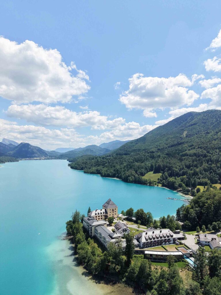 Das Rosewood Schloss Fuschl liegt am Ufer eines türkisfarbenen Sees, umgeben von Bergen und Wäldern.