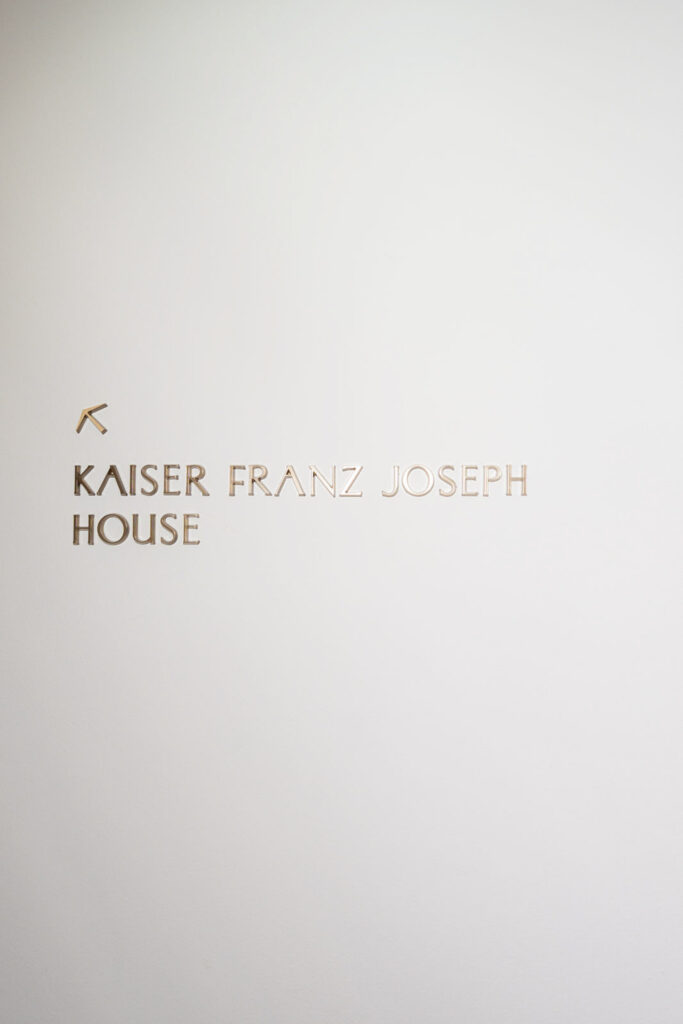 Wandschild, das nach oben zum Kaiser-Franz-Joseph-Haus im Rosewood Schloss Fuschl weist.